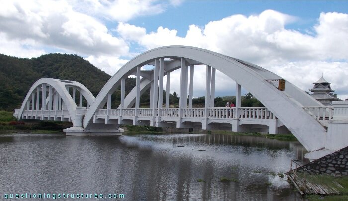 Reinforced concrete through-arch bridge over a river.