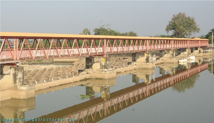 Through-truss bridge (Warren truss with verticals) over a weir.