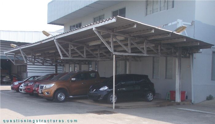 Attached steel carport with tapered trusses and suspension rods